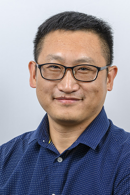 En man som bär glasögon och blå skjorta.